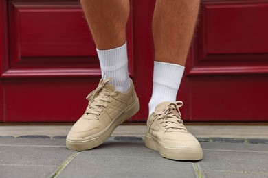 Man wearing pair of stylish sneakers outdoors, closeup