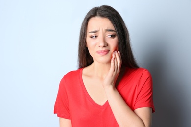 Woman with sensitive teeth on color background