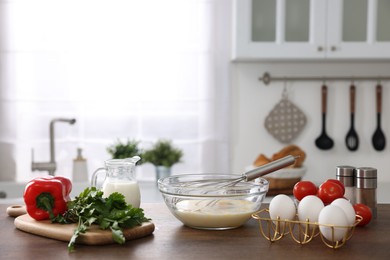 Photo of Whisk, bowl, beaten eggs and other ingredients on wooden table indoors, space for text