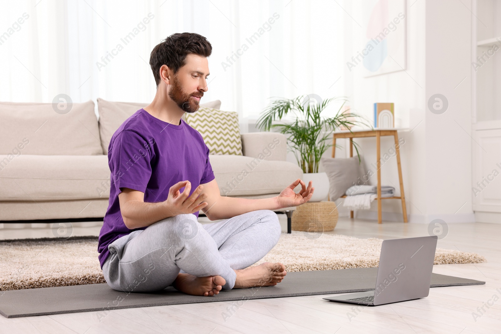 Photo of Man meditating near laptop at home, space for text