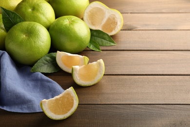 Photo of Whole and cut sweetie fruits on wooden table, space for text