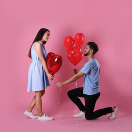 Photo of Lovely couple with heart shaped balloons on pink background. Valentine's day celebration