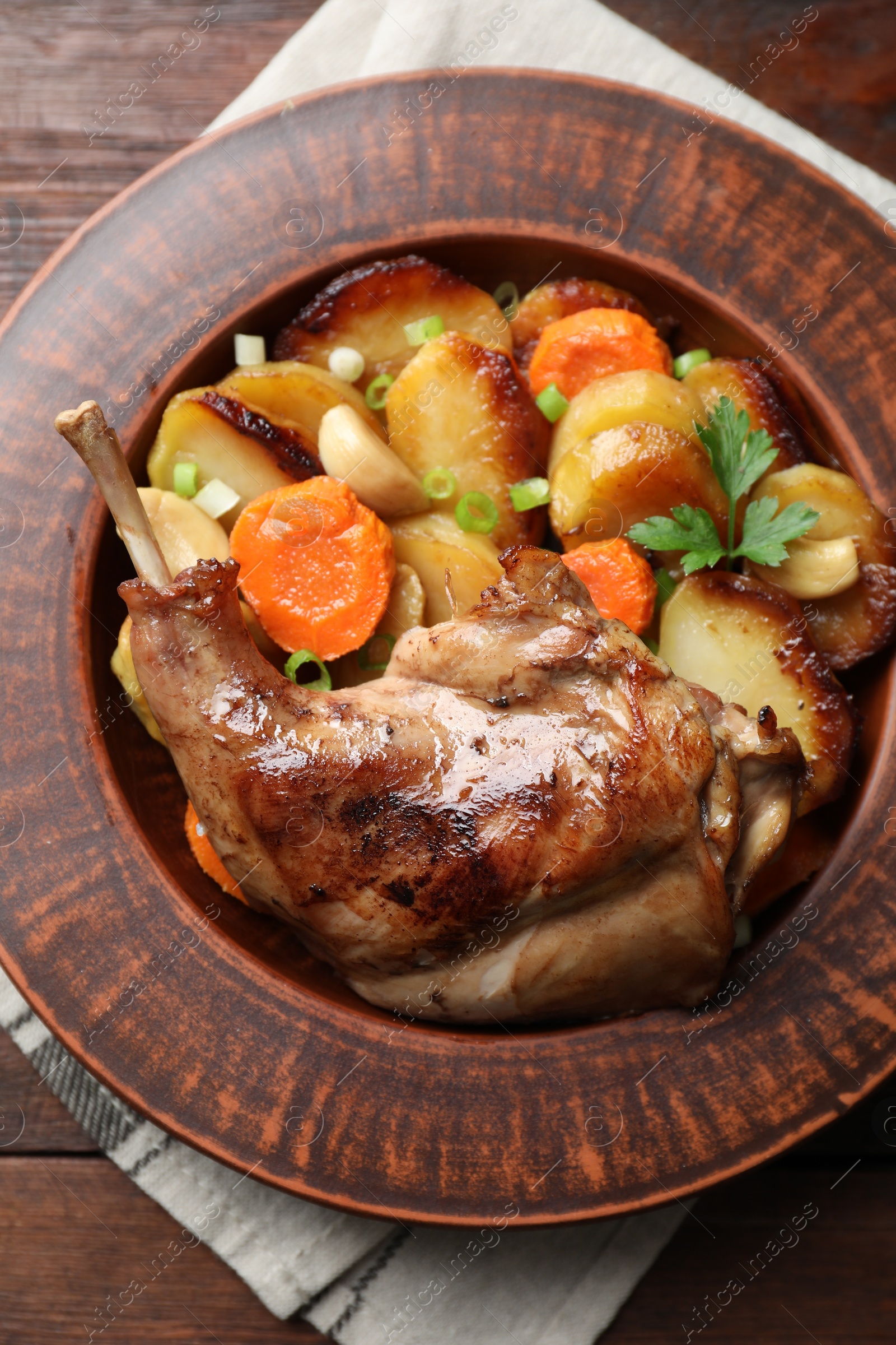 Photo of Tasty cooked rabbit meat with vegetables on wooden table, top view