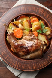 Tasty cooked rabbit meat with vegetables on wooden table, top view