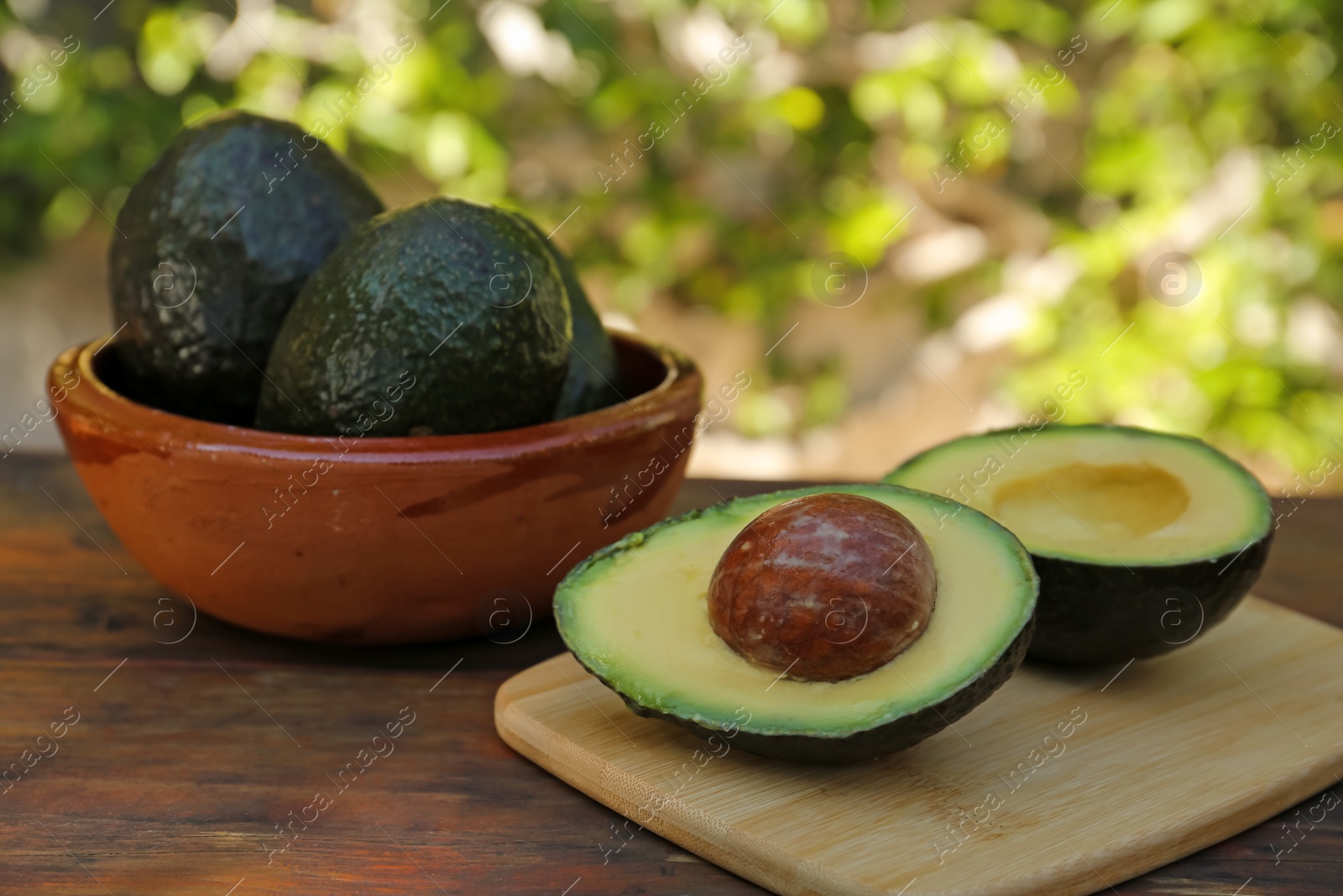 Photo of Tasty fresh avocados on wooden table outdoors