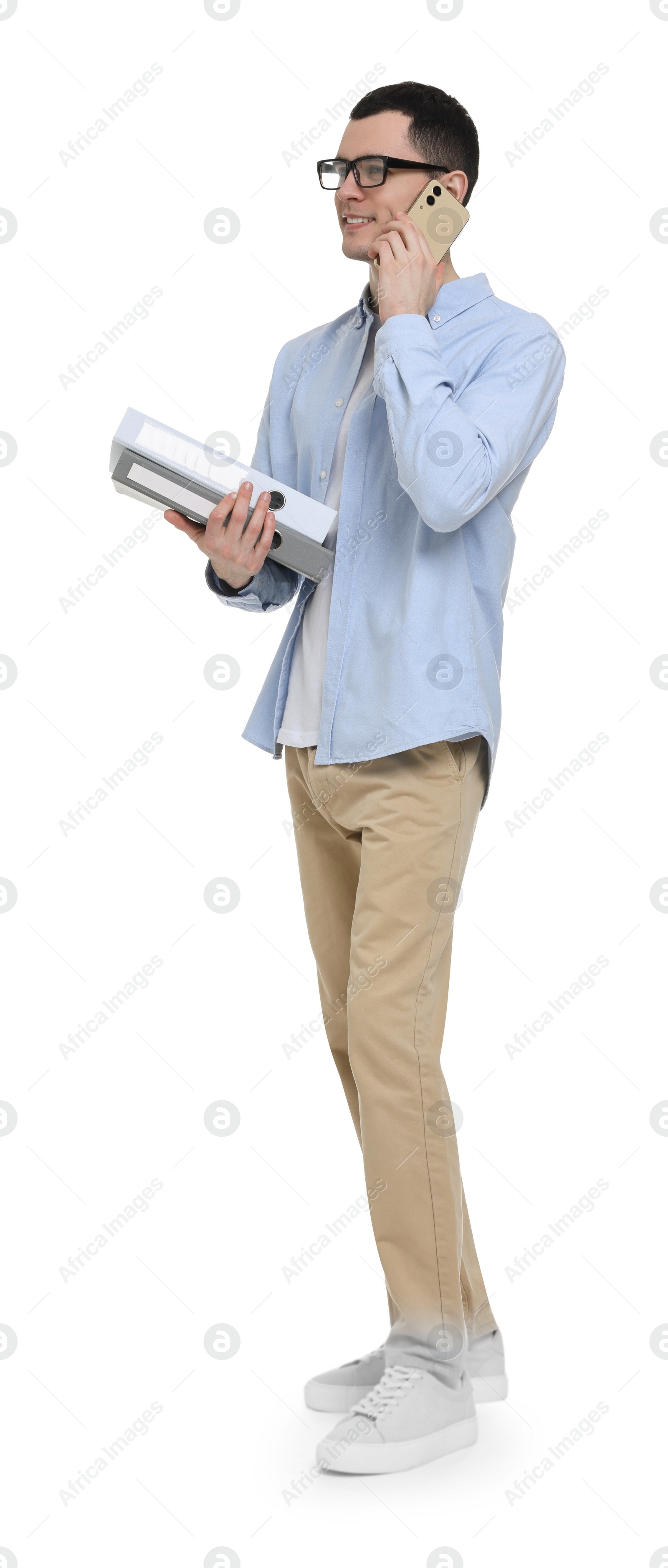 Photo of Young man in glasses holding folders and talking on mobile phone on white background