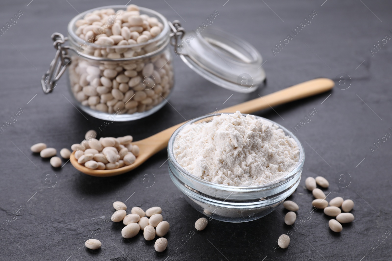 Bean flour and seeds on black table Photo of Bean flour and seeds on black table