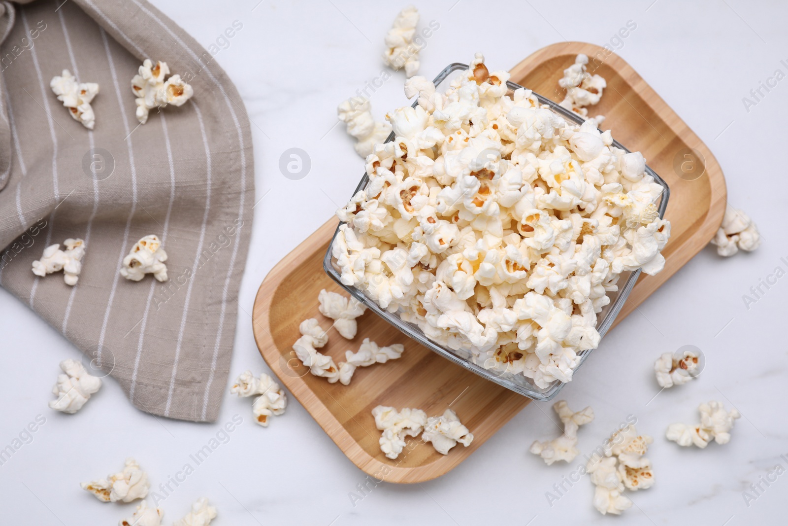 Photo of Bowl of tasty popcorn on white table, flat lay