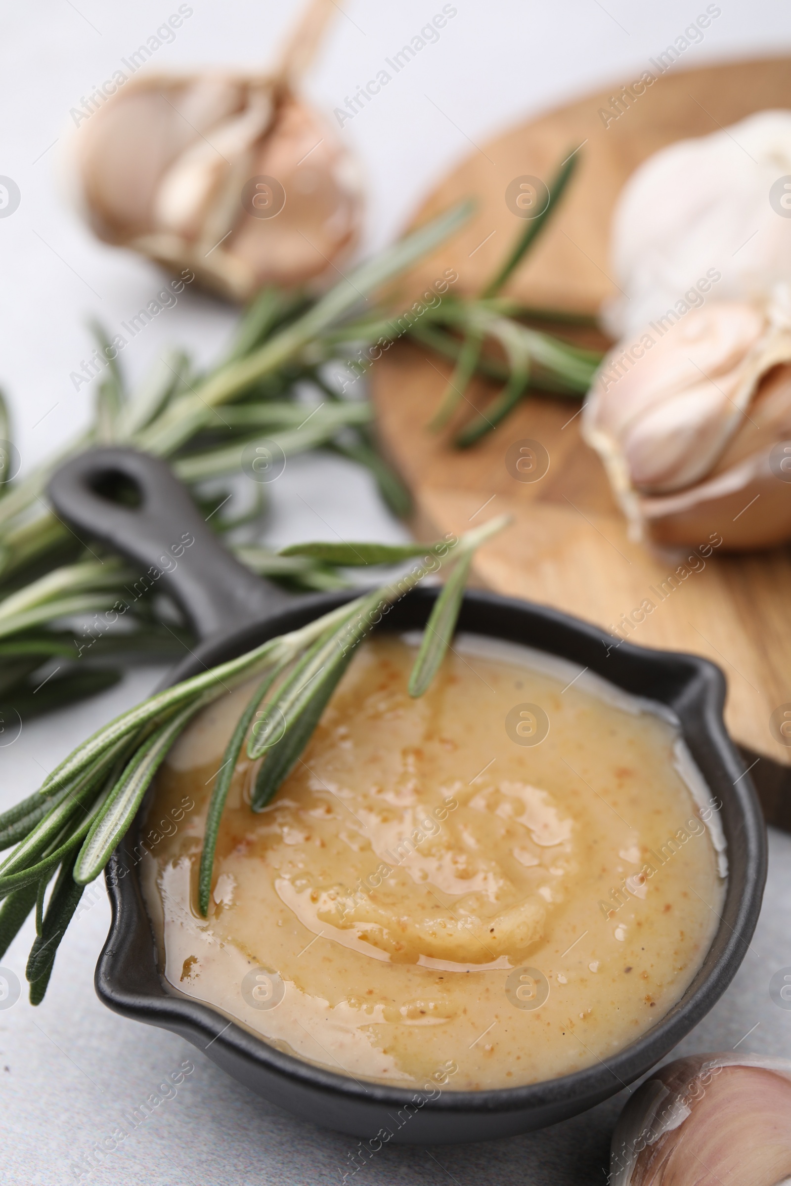 Photo of Delicious turkey gravy, rosemary and garlic on table, closeup