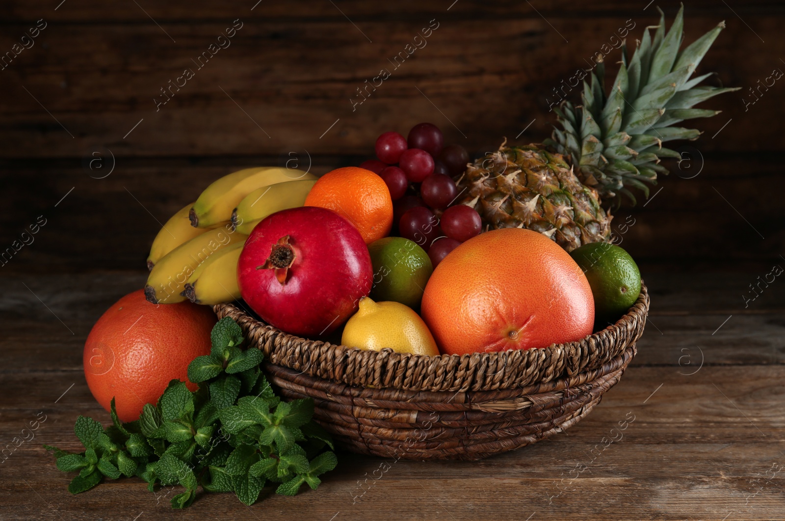 Photo of Wicker bowl with different ripe fruits on wooden table