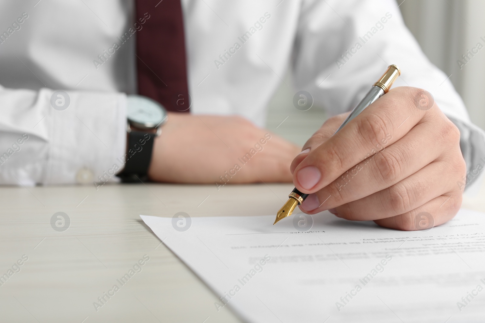 Photo of Notary signing document at wooden table, closeup