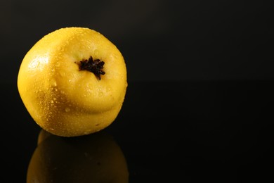 Tasty ripe quince with water drops on black mirror surface