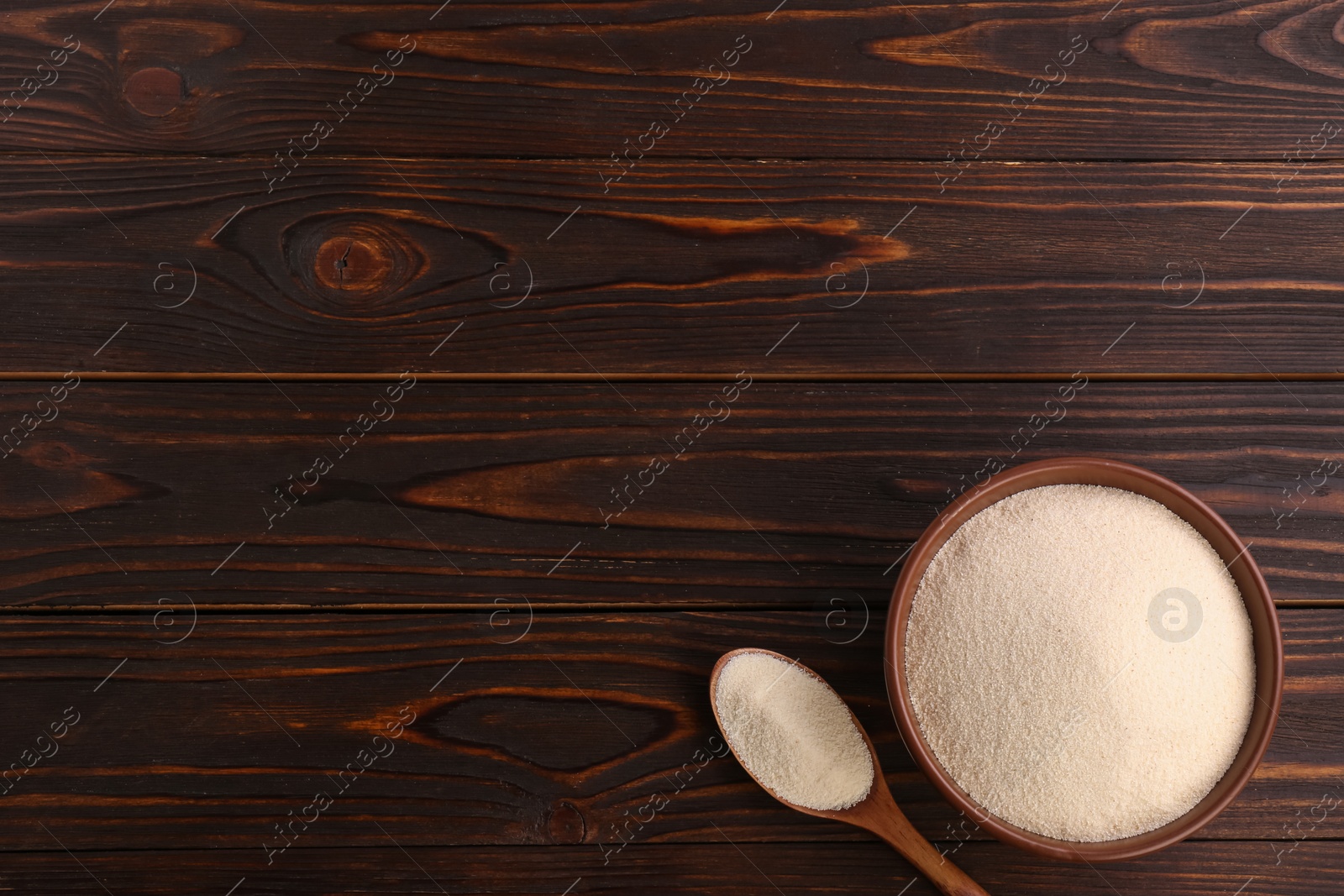 Photo of Uncooked organic semolina on wooden table, flat lay. Space for text