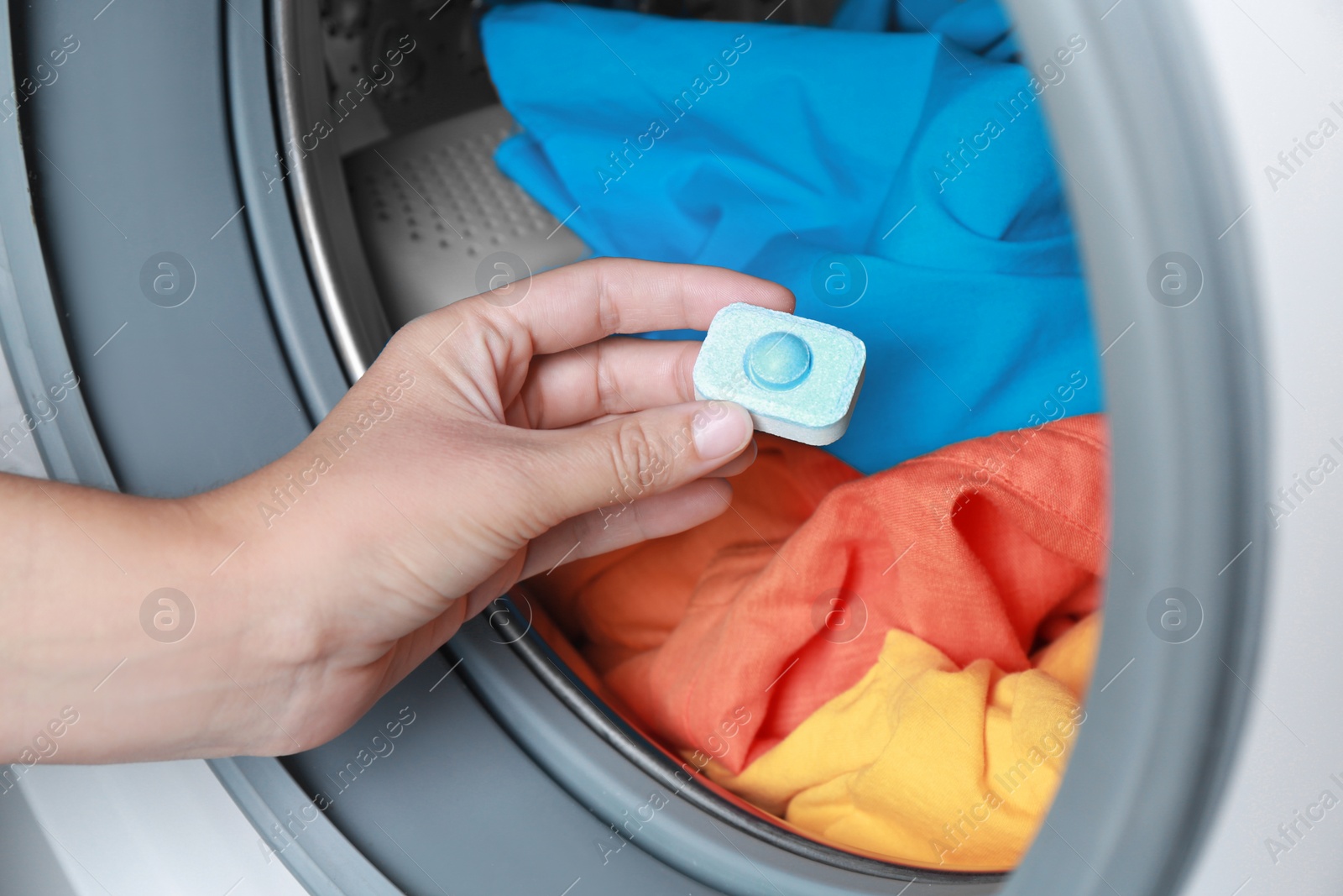 Photo of Woman putting water softener tablet into washing machine, closeup