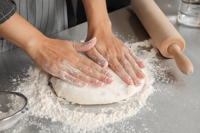Photo of Woman making dough for pastry on table