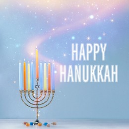 Image of Happy Hanukkah. Menorah with candles and dreidels on table against light blue background