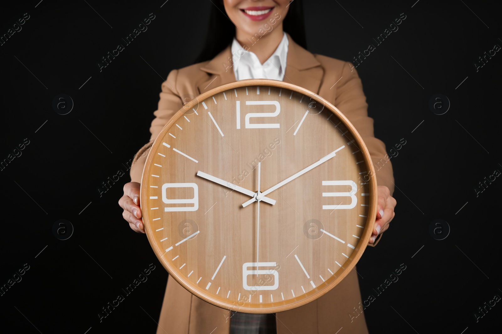 Photo of Businesswoman holding clock on black background, closeup. Time management