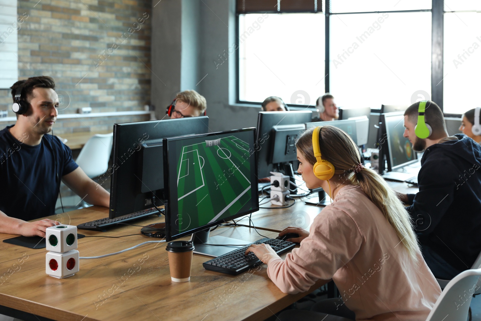 Photo of Group of people playing video games in internet cafe