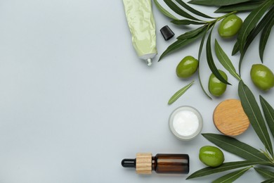 Photo of Cosmetic products with olive essential oil on light grey background, flat lay. Space for text