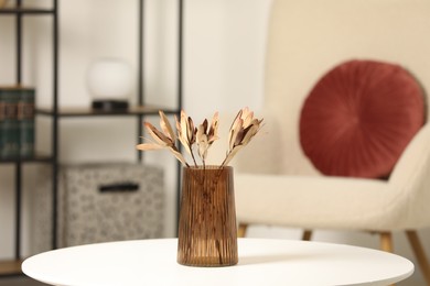 Vase with beautiful dried leucadendron plants on white table in living room