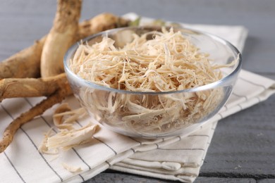 Photo of Grated horseradish and roots on grey wooden table, closeup