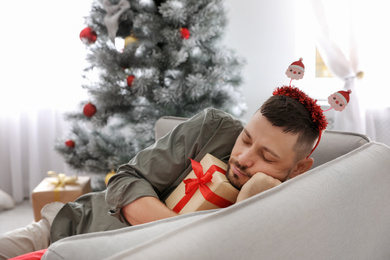 Photo of Man with gift box sleeping on sofa after New Year party