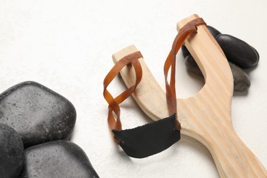 Photo of Wooden slingshot with stones on white background, closeup