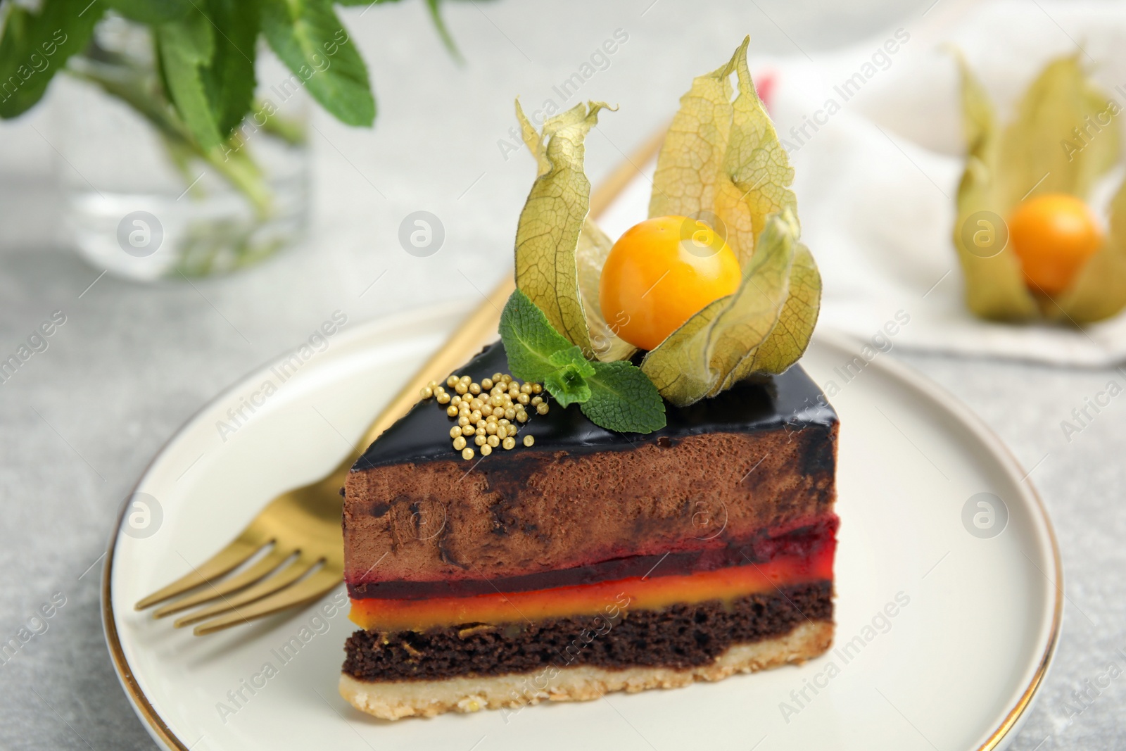 Photo of Piece of tasty cake decorated with physalis fruit on light grey table