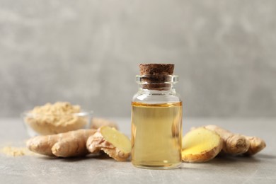 Glass bottle of essential oil and ginger root on grey table