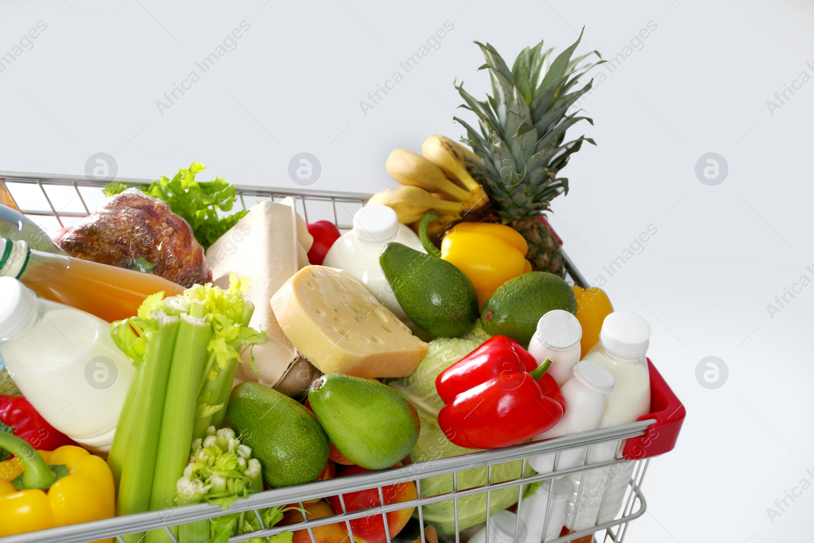 Photo of Shopping cart full of groceries on grey background, closeup