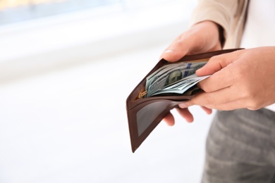 Photo of Man holding wallet with money indoors, closeup. Space for text