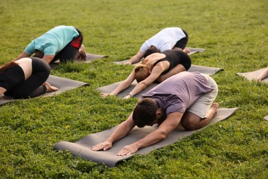 Photo of Group of people practicing yoga on mats outdoors