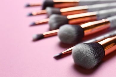 Photo of Different makeup brushes on pink background, closeup. Space for text