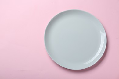 Photo of Empty ceramic plate on pink background, top view. Space for text