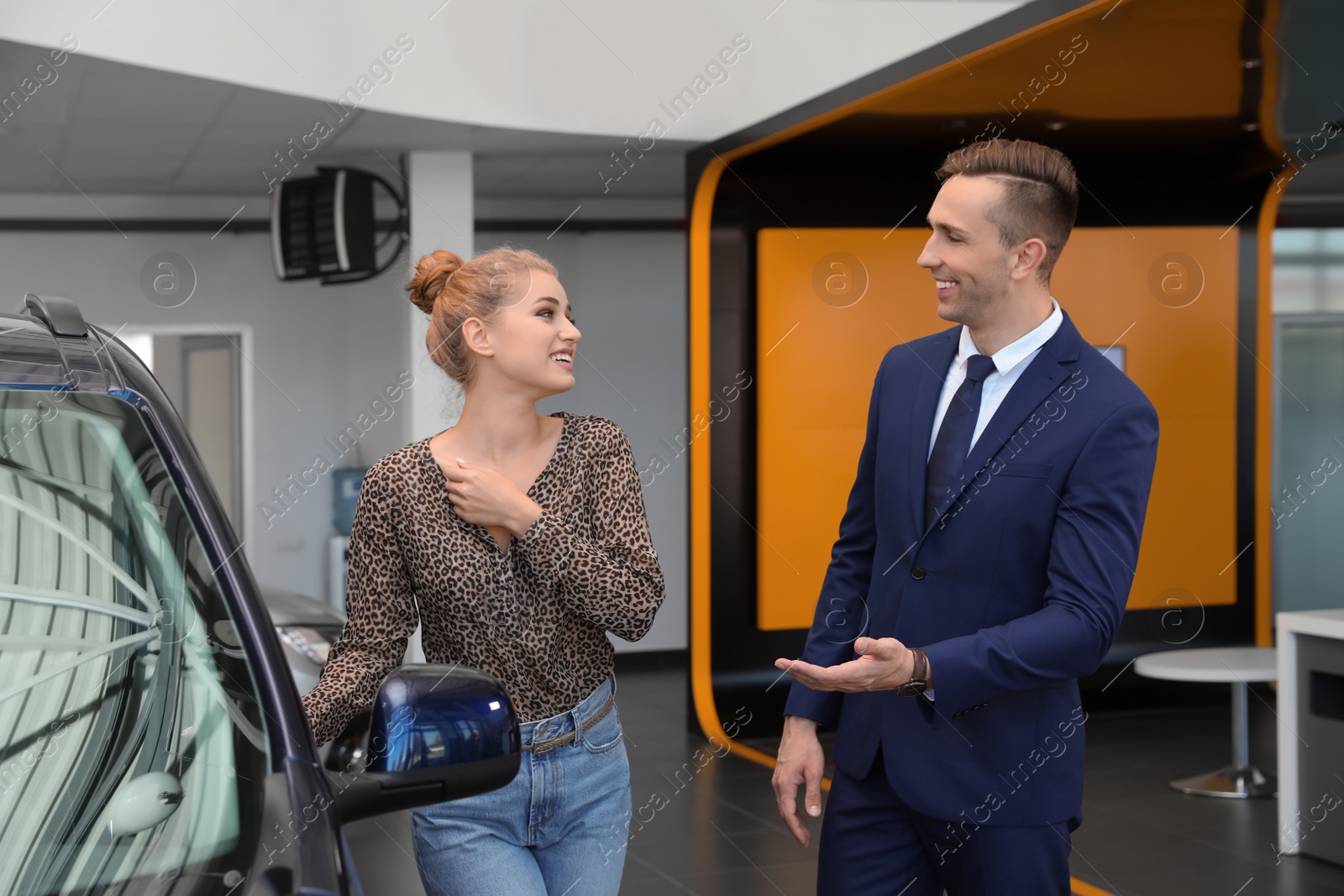 Photo of Young car salesman working with client in dealership