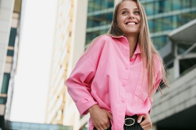 Photo of Beautiful young woman in stylish shirt on city street, space for text