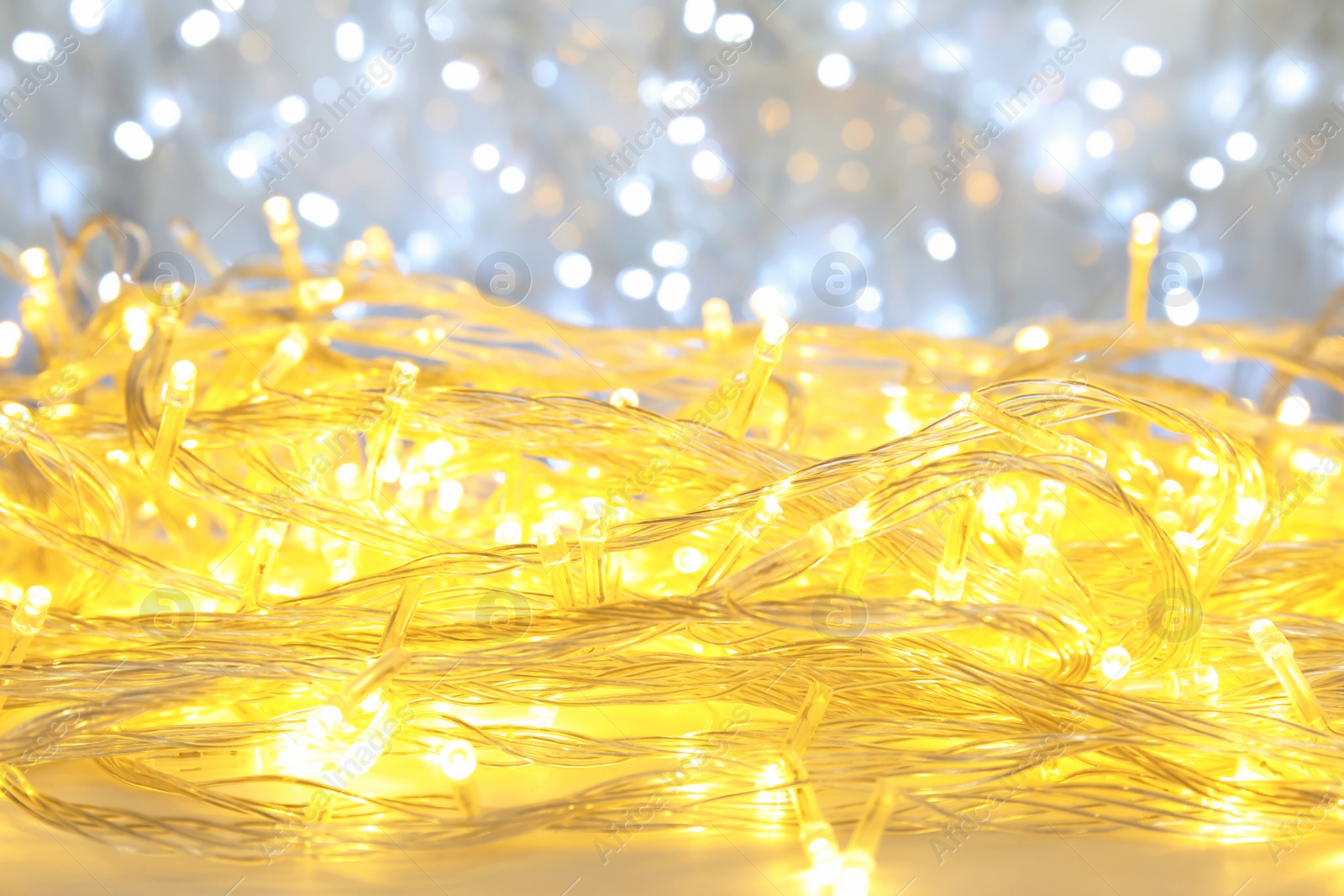 Photo of Glowing Christmas garland on light background, closeup