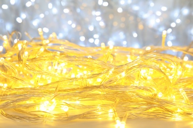 Photo of Glowing Christmas garland on light background, closeup