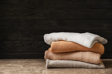 Photo of Stack of warm knitted clothes on table