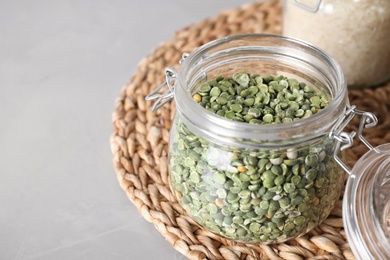 Photo of Dried peas in glass jar on grey table, closeup. Space for text