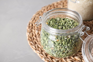 Dried peas in glass jar on grey table, closeup. Space for text