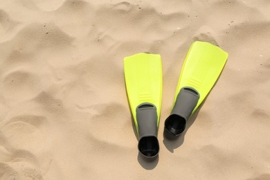 Photo of Pair of yellow flippers on sand, top view. Space for text