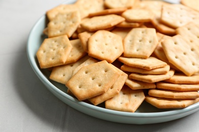 Photo of Plate with delicious crackers on light table, closeup