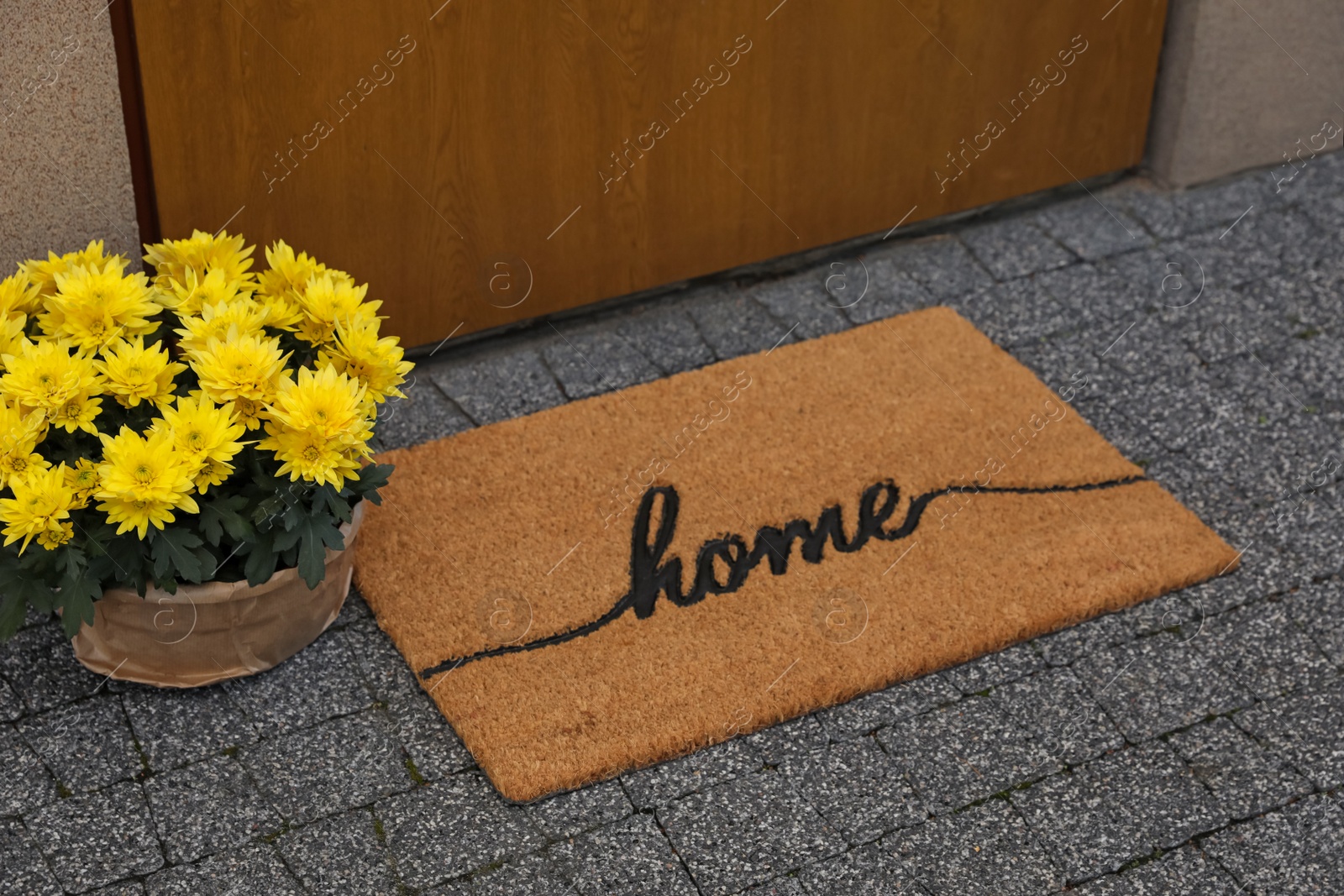 Photo of Doormat with word Home and flowers near entrance outdoors