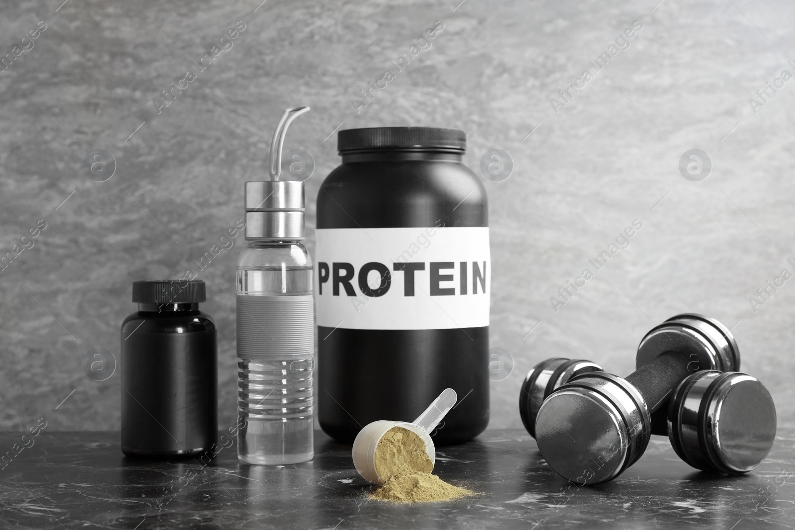 Photo of Hemp protein powder in measuring spoon, jars, bottle and dumbbells on table