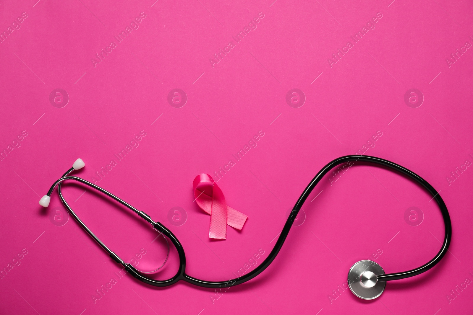 Photo of Breast cancer awareness. Pink ribbon and stethoscope on color background, flat lay. Space for text