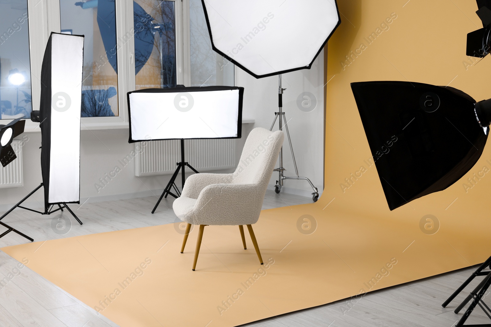 Photo of Interior of modern photo studio with armchair and professional lighting equipment