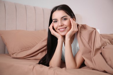 Photo of Woman lying in comfortable bed with beige linens