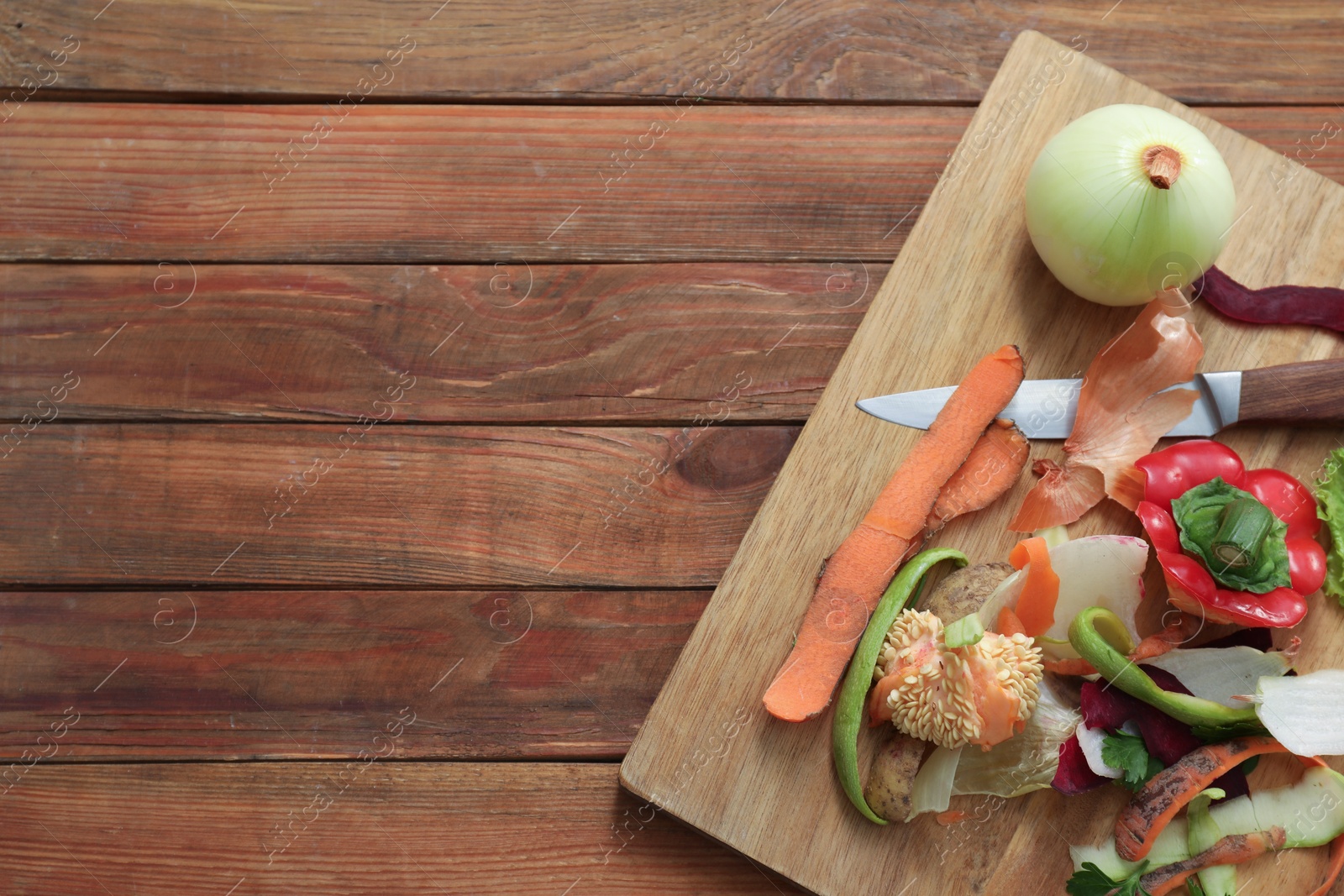 Photo of Peels, knife and fresh vegetables on wooden table, top view. Space for text