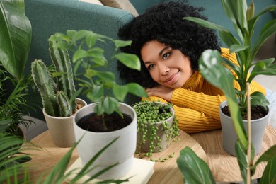 Photo of Relaxing atmosphere. Woman near many different potted houseplants indoors